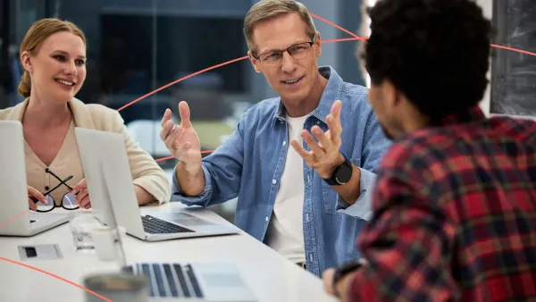 Team of professionals engaged in a discussion around laptops during a business meeting
