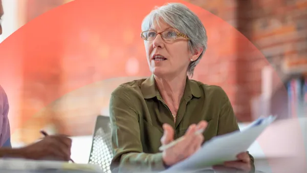 Professional woman speaking to someone, reviewing and holding a paper document.