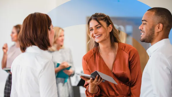Colleagues smiling to each other, while holding notebooks and tablets.