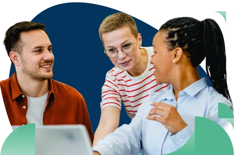Three diverse professionals in casual attire having a discussion at a table with laptop