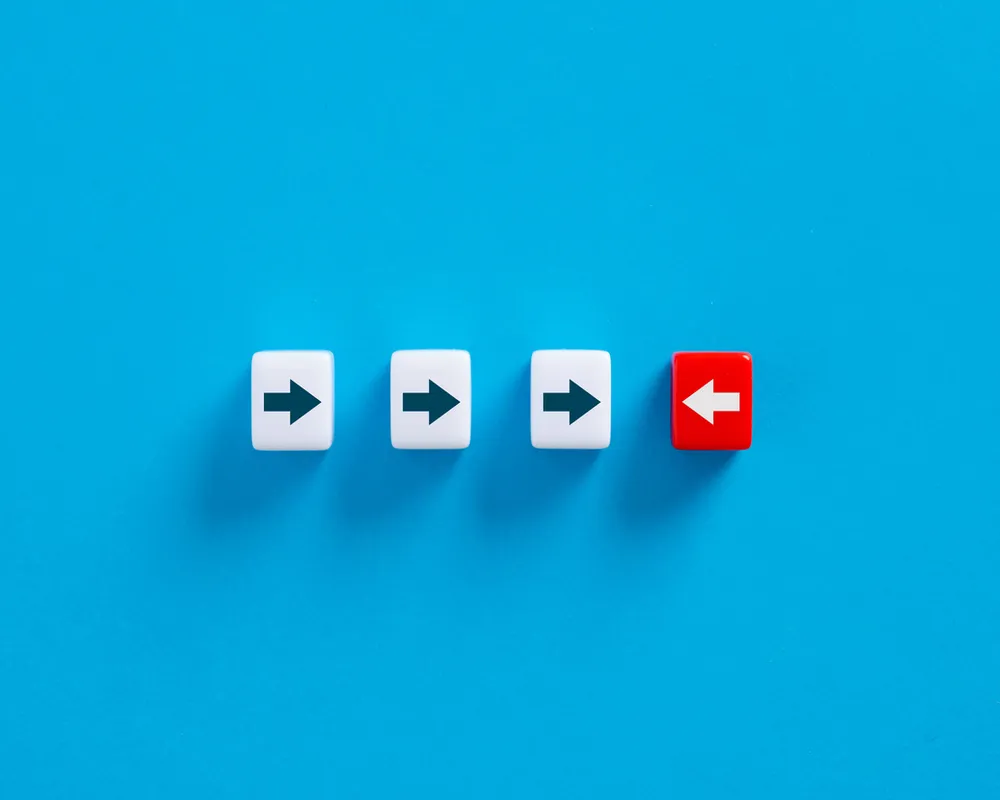 Three white forward arrows and one red backward arrow on bright blue background symbolizing resistance to change