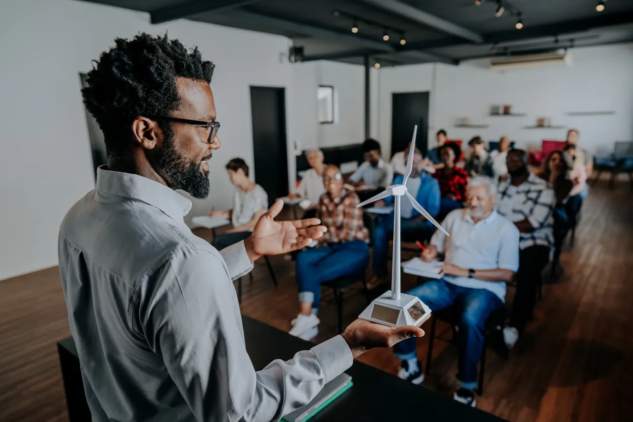 Speaker gesturing to engaged audience in bright modern classroom setting