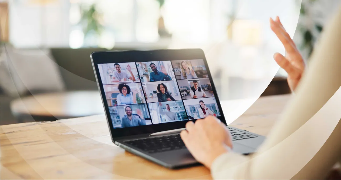 Person participating in an online video conference, engaging with multiple colleagues on a laptop screen.