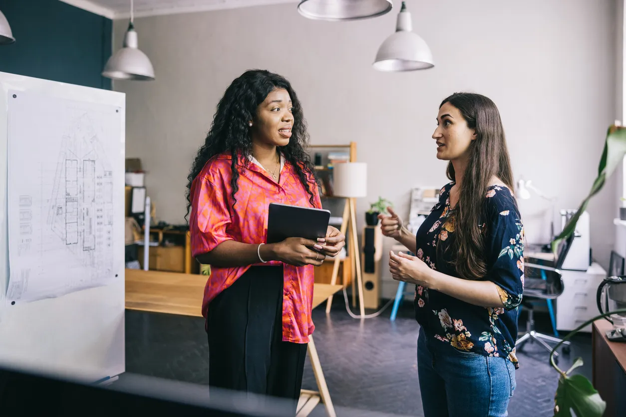 Two women standing and talking in a modern office space