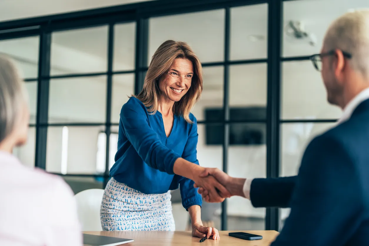 Businesswoman shaking hands with a man in an office setting