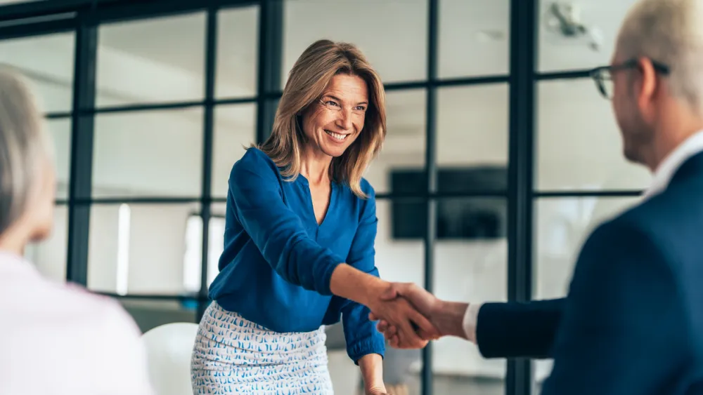 Businesswoman shaking hands with a man in an office setting