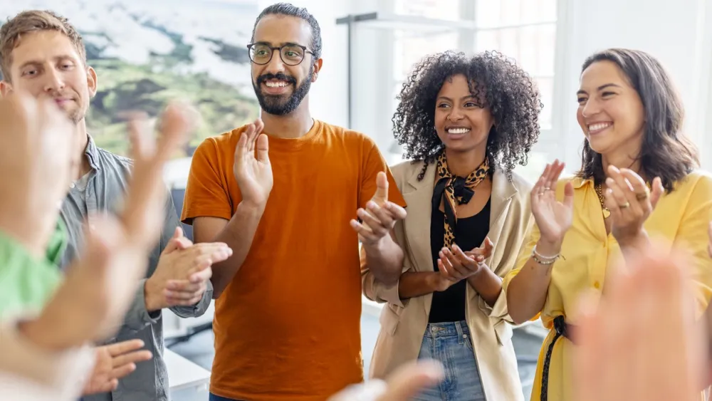 Group of diverse people smiling and applauding indoors