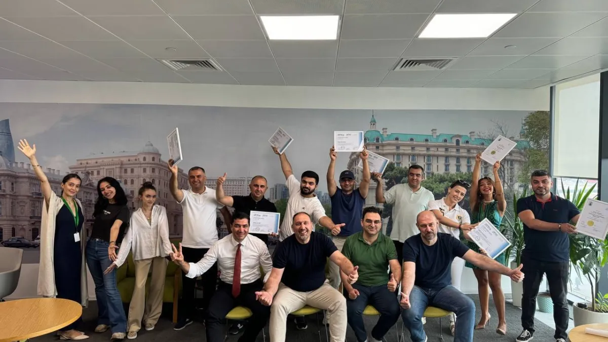 PMO.az team members gathered together joyously showing their certificates.