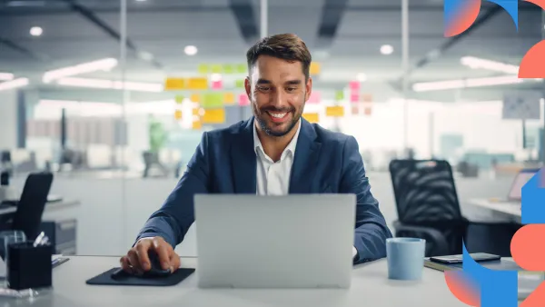 Professional in business attire sitting at desk with laptop, smiling in bright modern office