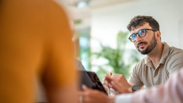 Man wearing glasses attentively listening in a meeting