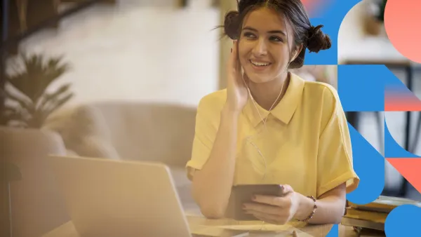 Professional woman working on a laptop, smiling while on a video call.